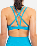 Back view of the Azure Blue Nexletica Synergy Sports Bra showing the strappy crossed back and tonal NEXLETICA underbust band