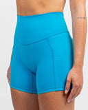 Close-up side detail of the Azure Blue Nexletica Synergy Rise Shorts showing the dual side pockets and tonal NEXLETICA branding